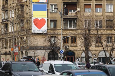 Bükreş, Romanya - 15 Mart 2022: Ukrayna bayrağı, Bükreş 'in merkezindeki bir binanın duvarında Rusya' nın kendilerine karşı açtığı savaştan ağır etkilenen Ukrayna halkıyla dayanışma içinde..
