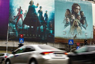 Bucharest, Romania - March 16, 2022: Two extra large banners advertising The Matrix Resurrections and Dune movies are displayed on the wall of a under renovation building in downtown Bucharest. clipart