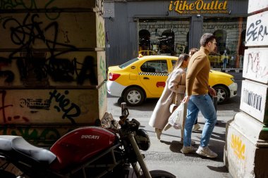 Bükreş, Romanya - 22 Mart 2022: Akademi Caddesi 'ndeki bir binanın mimari kemerlerinin önünde yürüyen insanlar görülüyor.