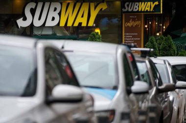 Bükreş, Romanya - 18 Haziran 2021: Bükreş şehir merkezindeki park halindeki arabaların üzerinde bir Subway fast food restoranının logosu görülüyor.