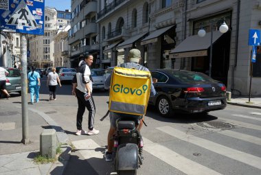 Bükreş, Romanya - 19 Temmuz 2022: Bir Glovo gıda dağıtım kuryesi Romanya 'nın Bükreş kentinde gıda dağıtıyor.
