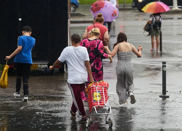 Bükreş, Romanya - 17 Haziran 2022: Şiddetli yağmurda insanlar karşıdan karşıya geçiyor.