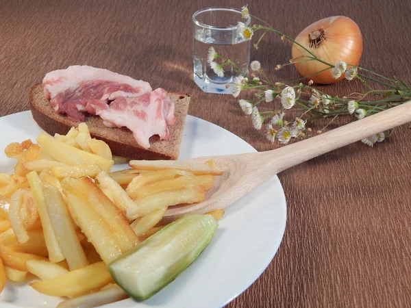 Patate fritte, pancetta, cipolle e il cucchiaio di legno, camomilla, un bicchierino di vodka — Foto Stock