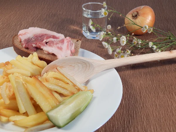 Patate fritte, pancetta, cipolle e il cucchiaio di legno, camomilla, un bicchierino di vodka — Foto Stock