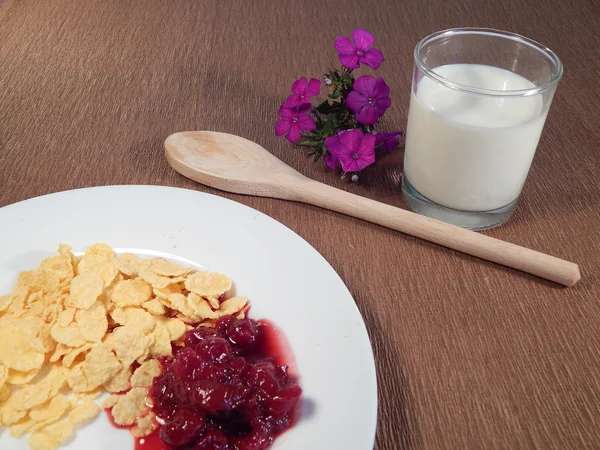 Copos de maíz, mermelada de cereza y flores, cuchara de madera — Foto de Stock