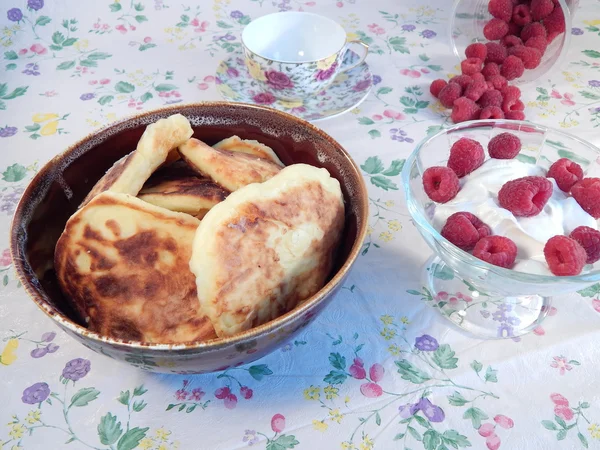 Pancakes in a clay pot and sour cream with raspberries — Stock Photo, Image