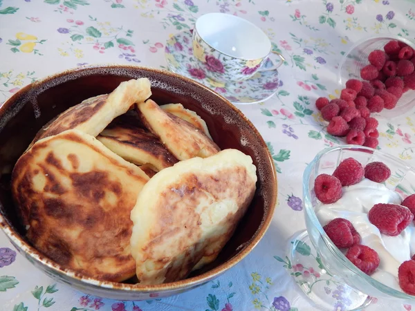 Pancakes in a clay pot and sour cream with raspberries — Stock Photo, Image