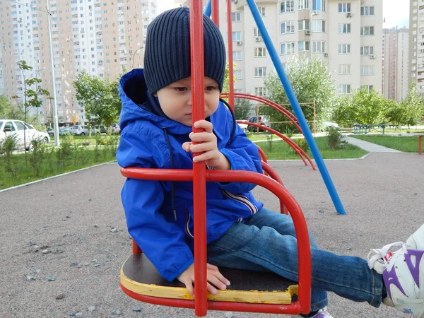 A child on a swing in the city — Stock Photo, Image