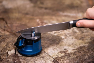 hand sharpening a knife blade with a special knife sharpener