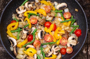fried mushrooms with tomatoes, onions, asparagus and vegetables in a frying pan