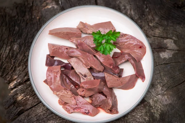 fresh raw beef liver on a plate on a dark wooden background