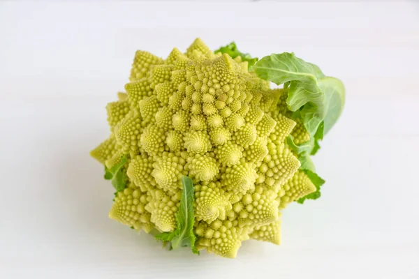Beyaz ahşap arka planda yeşil yapraklı Lezzetli Romanesco (brokoli)