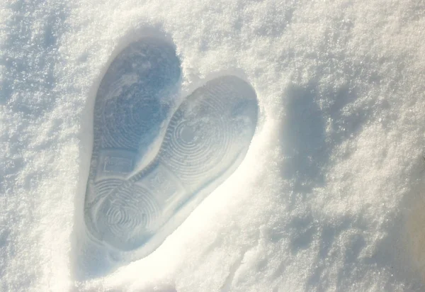 Frozen heart made by foot on white snow in winter