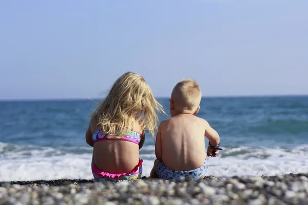 Junge und Mädchen sitzen am Strand — Stockfoto