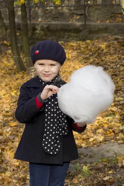 Beautiful girl eating cotton candy at the autumn park — Stock Photo, Image