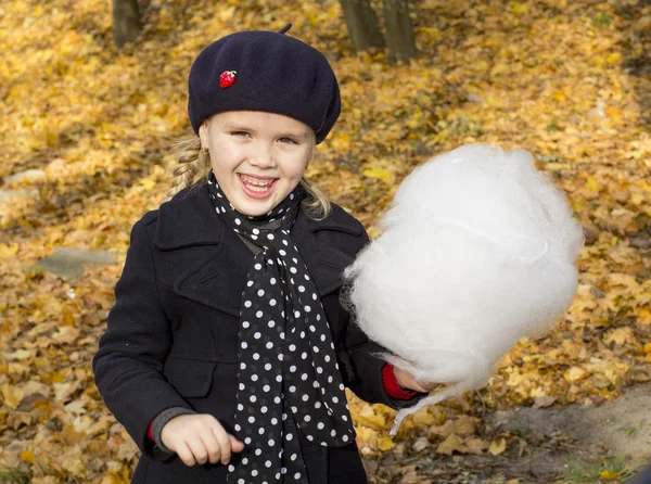 Beautiful girl eating cotton candy at the autumn park — Stock Photo, Image