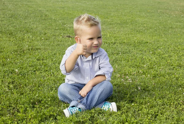 Chlapec seděl na trávě — Stock fotografie