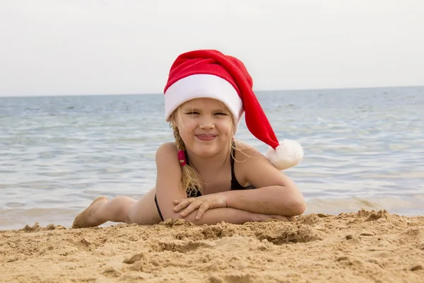 Dziewczyna w santa hat na plaży — Zdjęcie stockowe