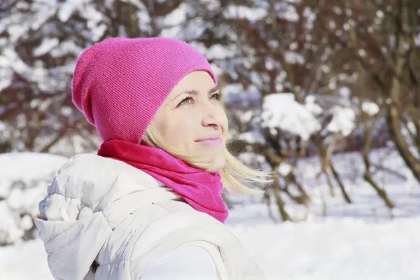 Flicka i rosa hatt tittar på vintersolen Royaltyfria Stockbilder