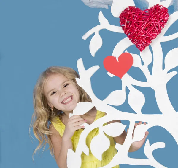 Chica bonita sonriendo y mirando sobre un árbol ornamental — Foto de Stock