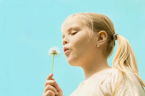 Meisje blazen op een paardebloem — Stockfoto