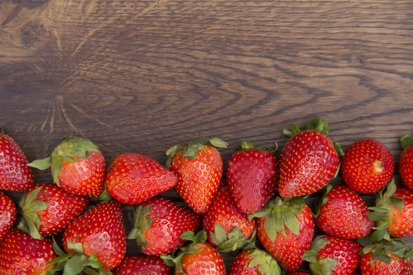 Aardbei verspreid over bruin houten oppervlak — Stockfoto