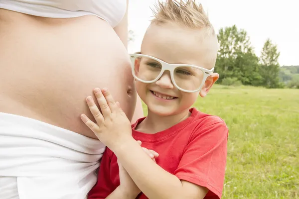 Menino ouvindo barriga grávida — Fotografia de Stock