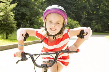 Kız bir parkta Bisiklete biniyor.