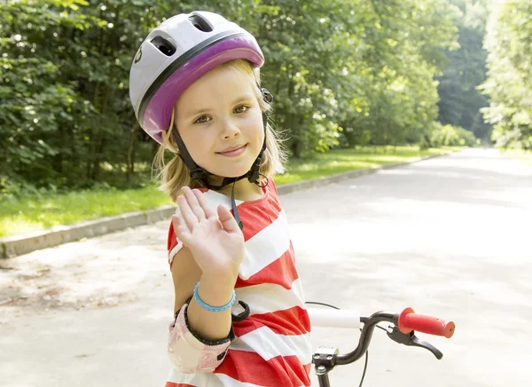 Kız bir parkta Bisiklete biniyor.