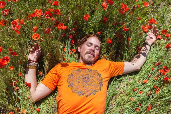 En man som ligger på gräset i blommor — Stockfoto