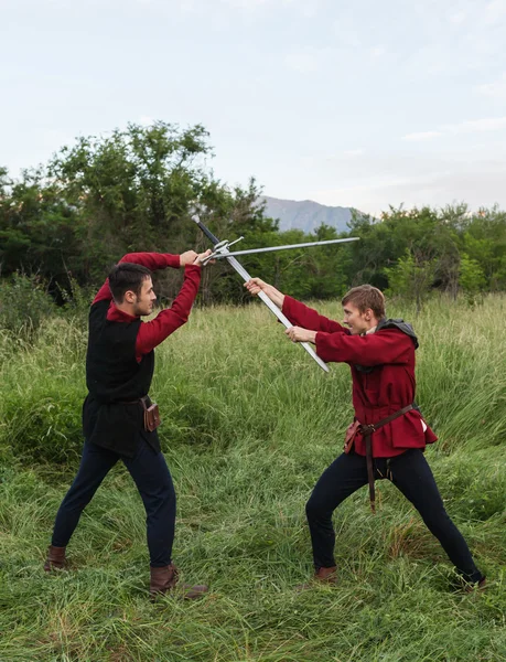 Cavaleiros lutando com espadas nos últimos raios do sol — Fotografia de Stock