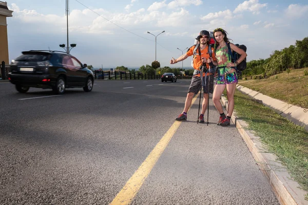 Dos amantes haciendo autostop, de pie con un cartel en blanco — Foto de Stock
