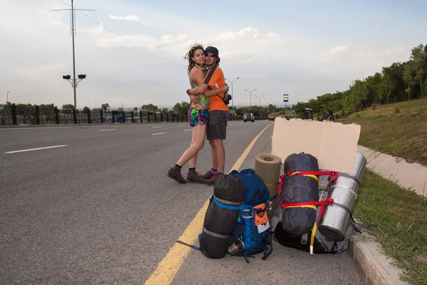 Dos amantes haciendo autostop, de pie con un cartel en blanco — Foto de Stock