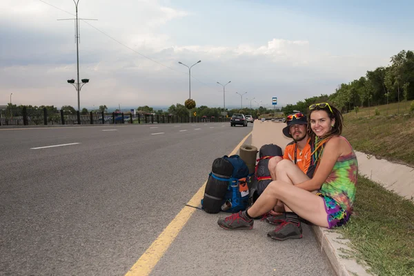 Dos amantes haciendo autostop, de pie con un cartel en blanco —  Fotos de Stock