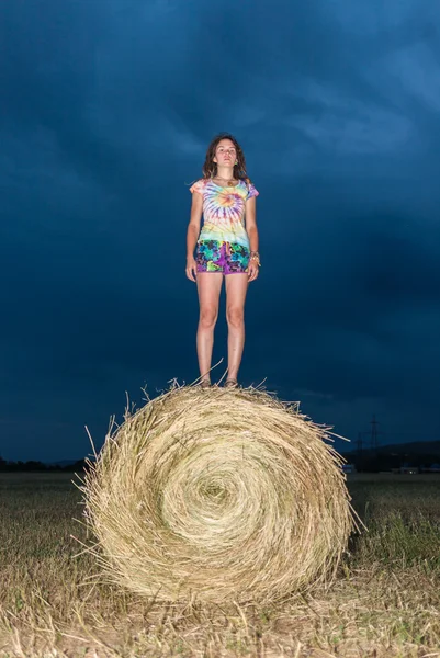 Flickan hoppar på ett hö-fält — Stockfoto