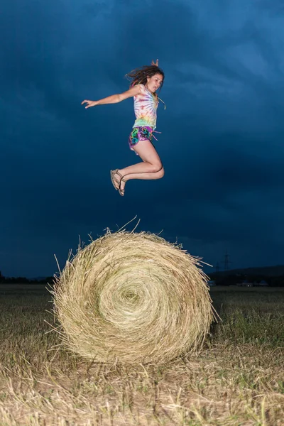 Girl jumping on a hay field — Stock Photo, Image