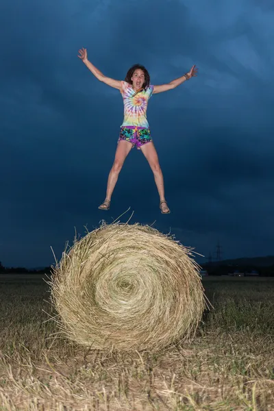 Pige hoppe på en hø felt - Stock-foto