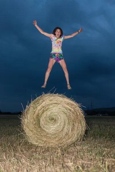 Meisje springen op een veld hooi — Stockfoto