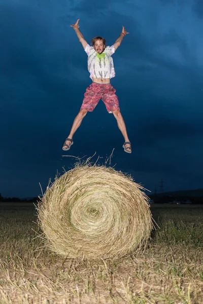 Man springen op een veld hooi — Stockfoto