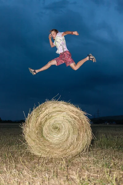 Uomo che salta su un campo di fieno — Foto Stock