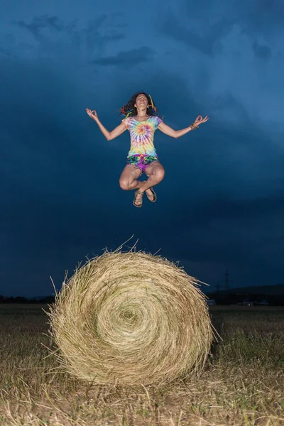 Flickan hoppar på ett hö-fält — Stockfoto