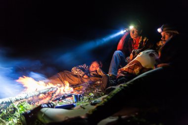 Bonfire in a camp in the mountains and the light of flashlights clipart
