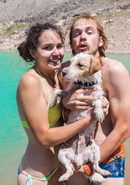 Lyckliga paret simmar i sjön med en liten hund — Stockfoto