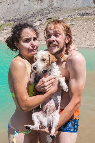 Happy couple swims in the lake with a small dog — Stock Photo, Image