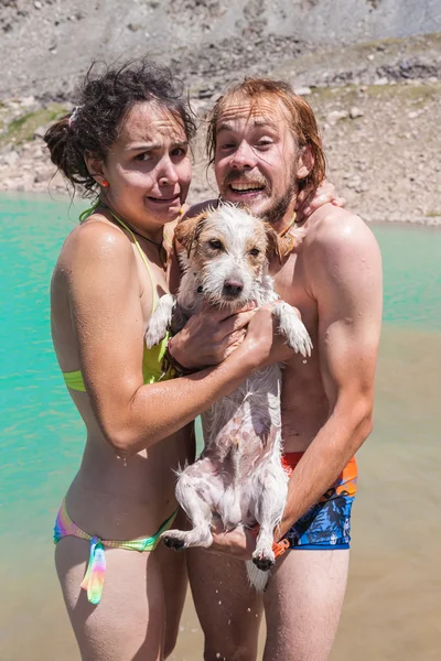 Feliz pareja nada en el lago con un perro pequeño — Foto de Stock