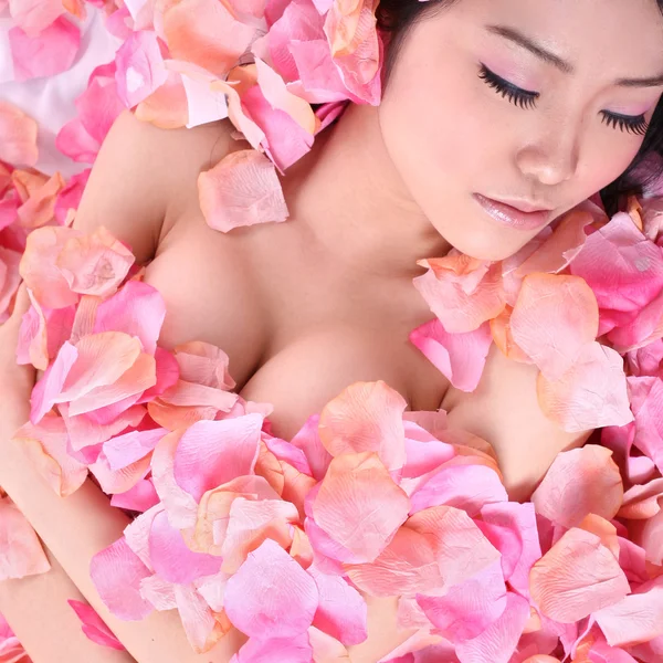 Aziatische meisje in roze bloemblaadjes — Stockfoto