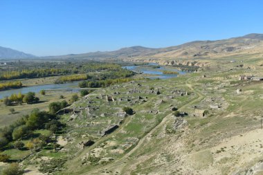 Gürcistan, Asya 'daki Uplistsikhe kaya mağarası şehrinden Mtkvari nehri veya Kura nehri manzarası. Arka planda sonbahar ağaçları ve tepeler olan nehir kıyısı.