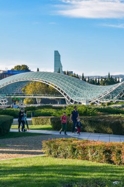 Tiflis, Gürcistan - 24 Ekim 2021: Gürcistan 'ın başkenti Rike Park' ta Barış Köprüsü, arka planda Kura Nehri üzerindeki yaya köprüsü