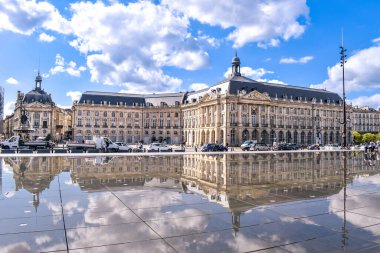 Bordeaux, Fransa - 17 Eylül 2021: Su Aynası, Place de la Bourse 'un önündeki Garonne nehrinin rıhtımındaki dünyanın en büyük yansıtma havuzu. Sokaktaki insanlar, bulutlu mavi gökyüzü