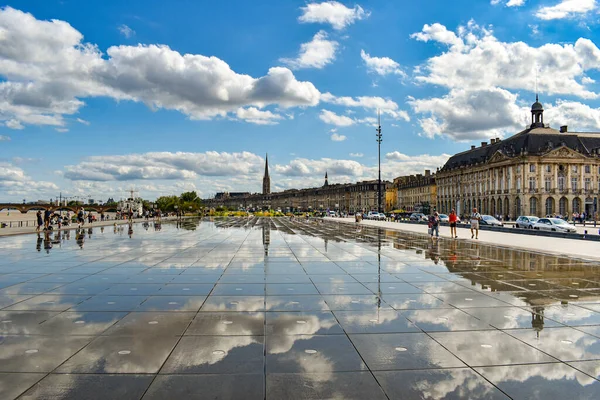 Bordeaux, Frankrijk - 17 sep 2021: Waterspiegel, 's werelds grootste spiegelbad aan de kade van de Garonne tegenover de Place de la Bourse. Mensen op straat, blauwe lucht met wolken — Stockfoto